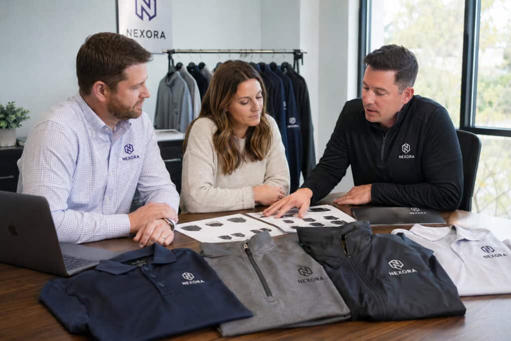 Corporate team reviewing custom embroidered polos, quarter-zips, and branded company apparel options