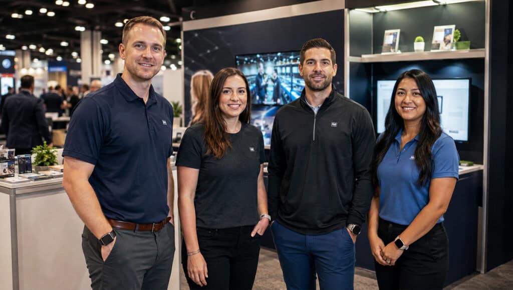Small business trade show team wearing coordinated embroidered polos and branded apparel at a professional exhibit booth
